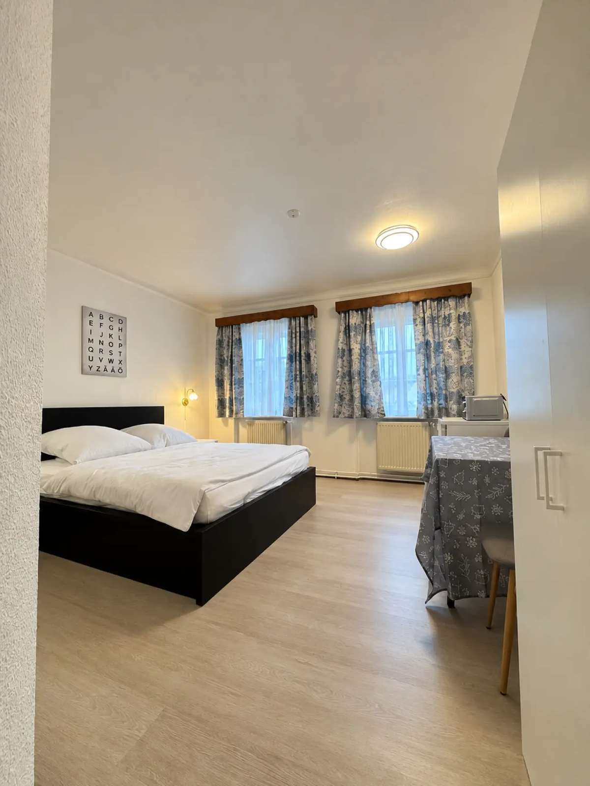 Doppelzimmer mit großem Bett, Vorhängen und Holzboden