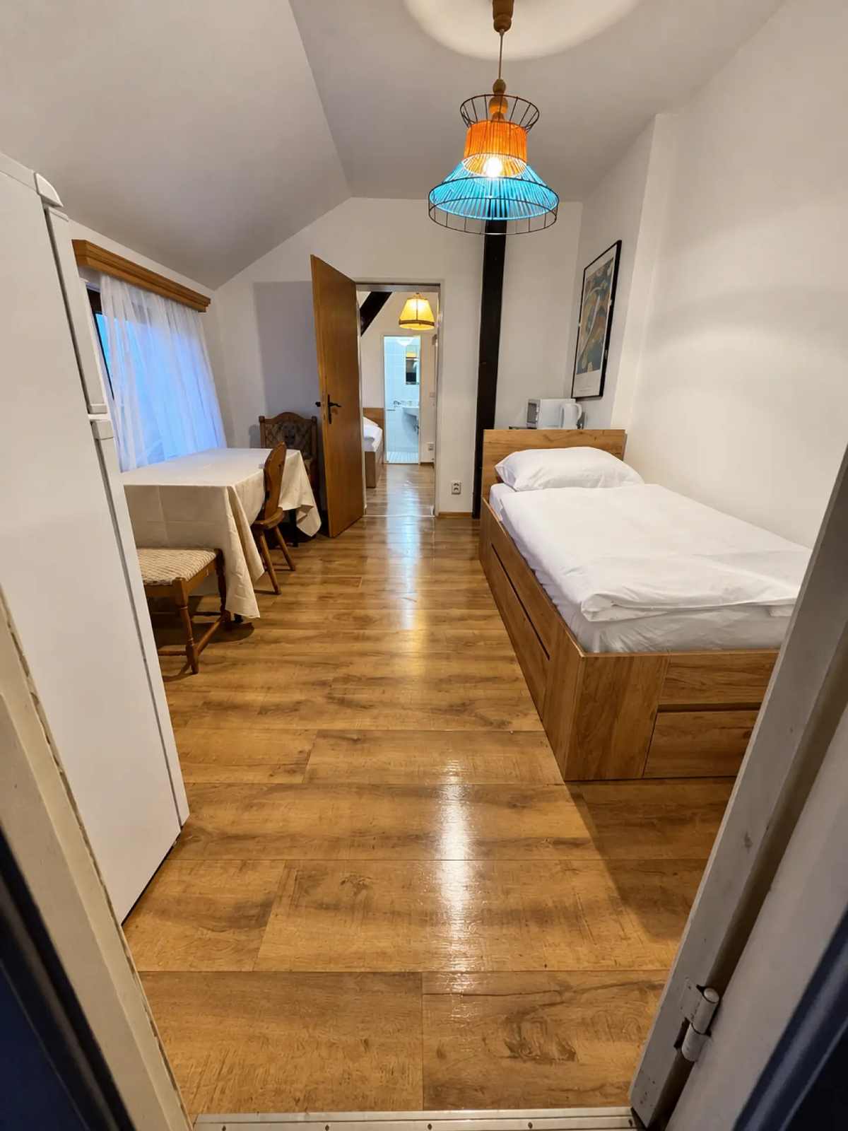Einzelzimmer mit Holzbett, Esstisch und Dachschräge